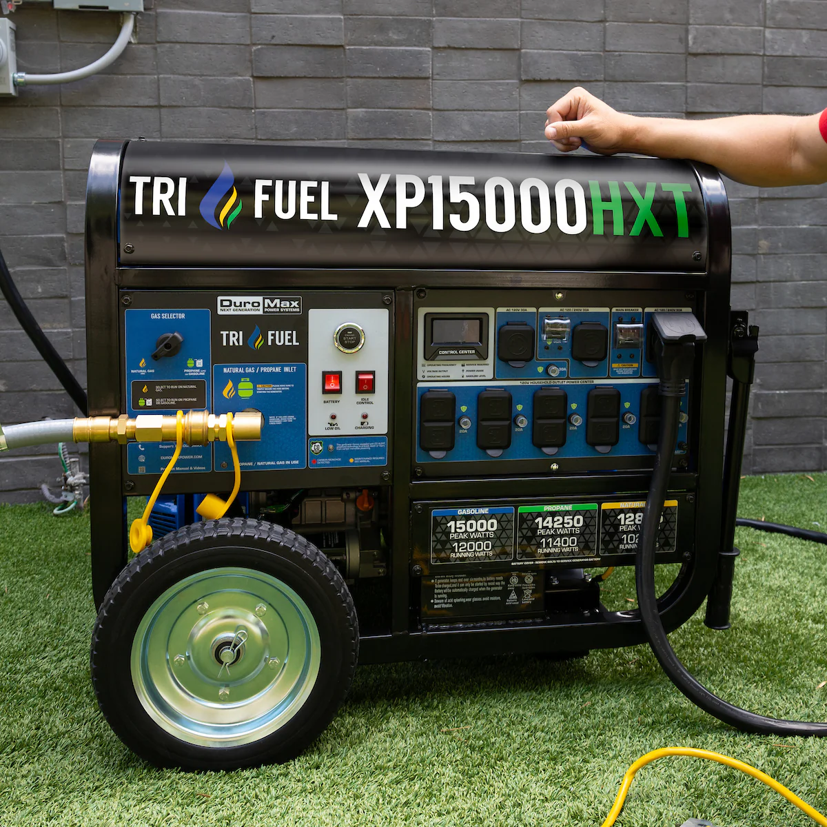 A DuroMax Tri Fuel Portable Generator ready for home backup with the natural gas connected and a heavy-duty generator cord plugged into the 50-Amp outlet.